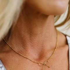 Ivy Dainty Bow Necklace in gold, worn
