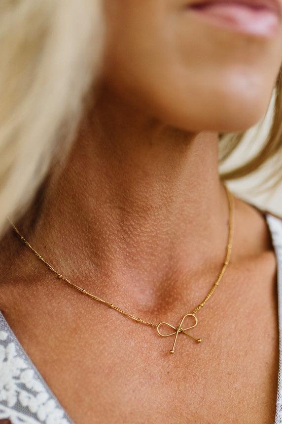 Ivy Dainty Bow Necklace in gold, worn
